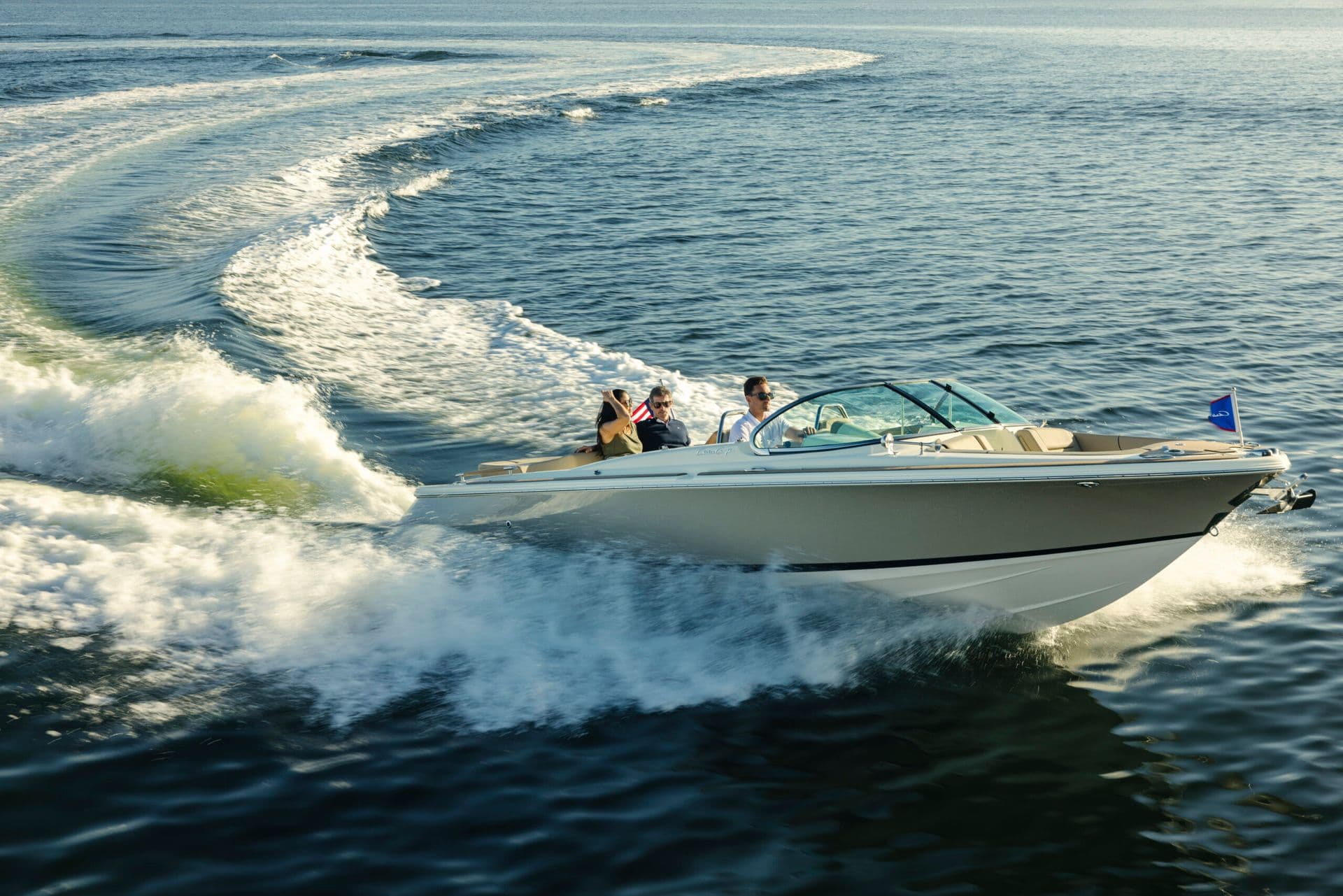 Chris-Craft Launch 25 GTe speedboat carrying passengers, turning across open water and leaving a broad foamy wake.
