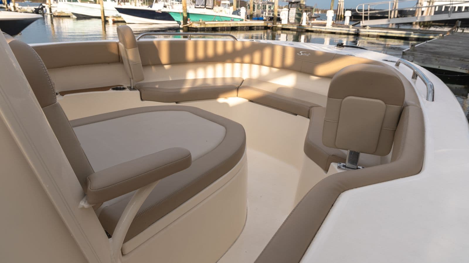 Scout 215 XSF bow seating area with wraparound cushioned benches and marina visible beyond the boat.