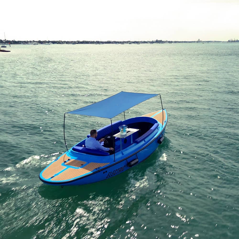 2024 Vision Marine Fantail 217
Blue Fantail-style recreational boat with canopy cruising on open water, viewed from above and slightly aft; one person seated at the helm.