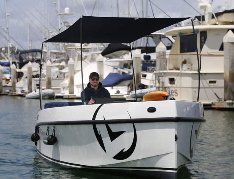 Vision Marine Volt 180 viewed from the bow, showing the front hull and canopy at a marina.