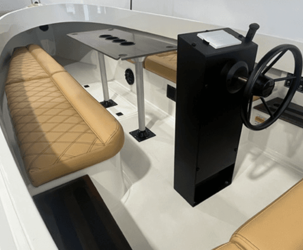 2024 Vision Marine Fantail 217 Interior of a white electric boat with tan cushioned seating, helm console and steering wheel, plus a small center table.