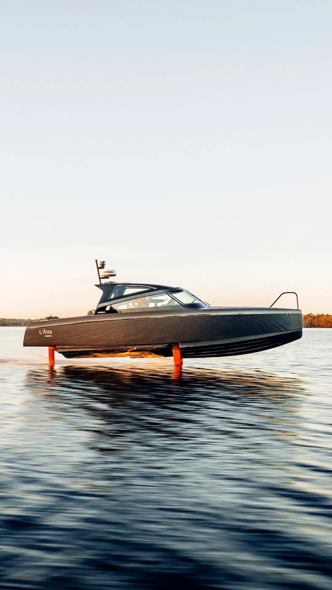 Candela C-8 electric hydrofoil boat cruising above calm water at sunset, with its submerged foils visible.