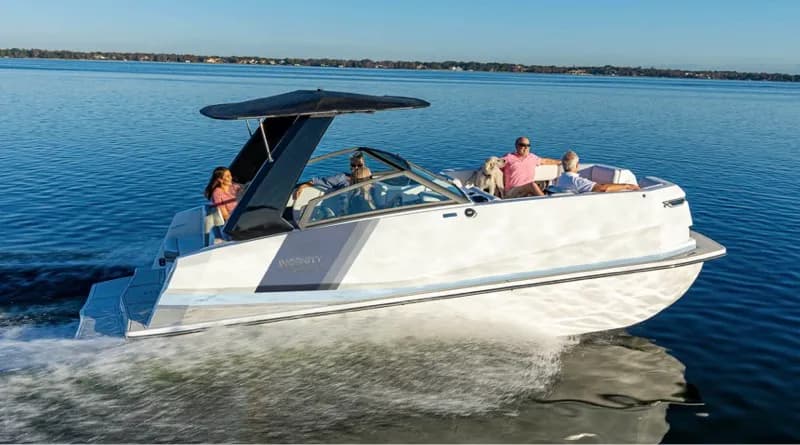 Ingenity 23E motorboat cruising on a lake, viewed from the starboard side with the bow to the right.
