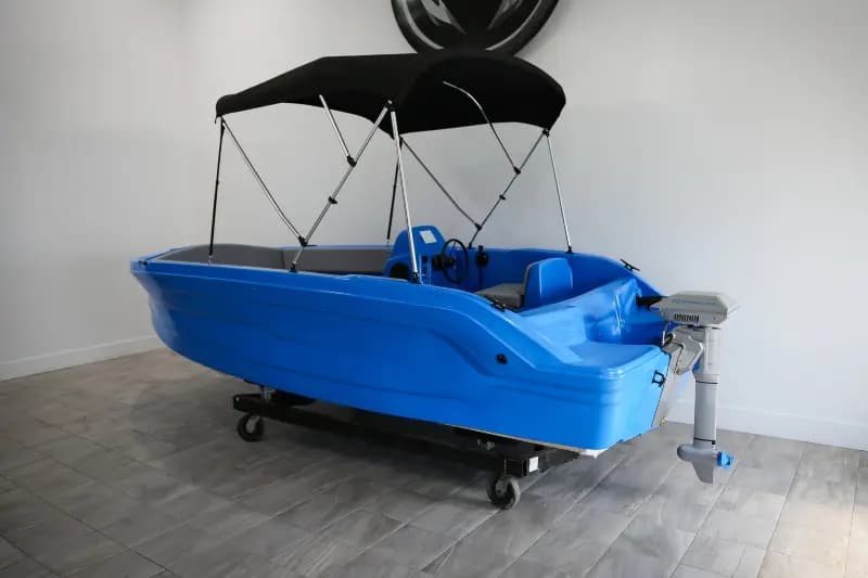 Blue Vision Marine Phantom boat with black canopy and outboard motor, displayed indoors on a wheeled trailer.