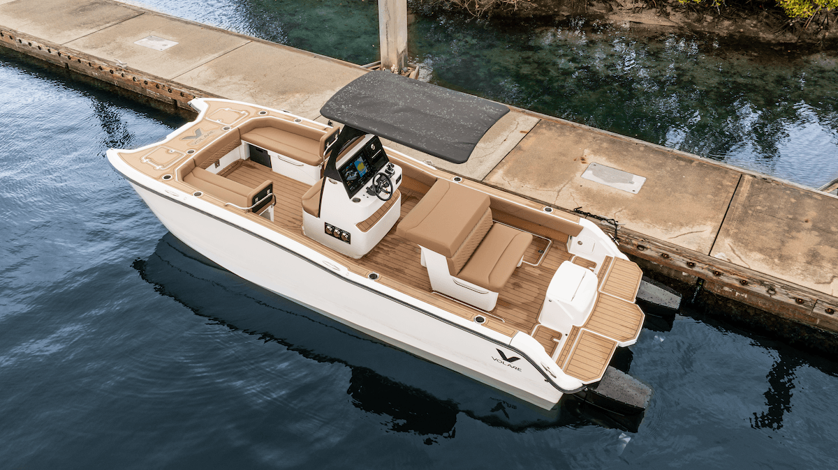Volare Artemis 23 powerboat docked in clear water, viewed from above, with tan seating, center console, black canopy, and swim platform at aft.