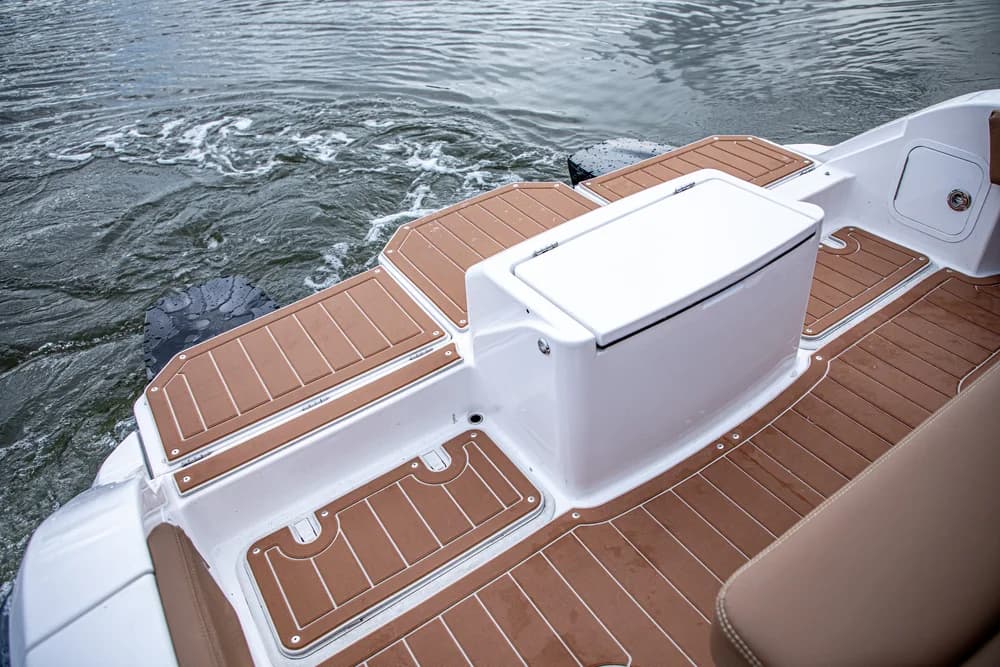 Rear deck and swim platform of Artemis 23e electric boat with teak-style flooring, central storage console, and rippling water behind.