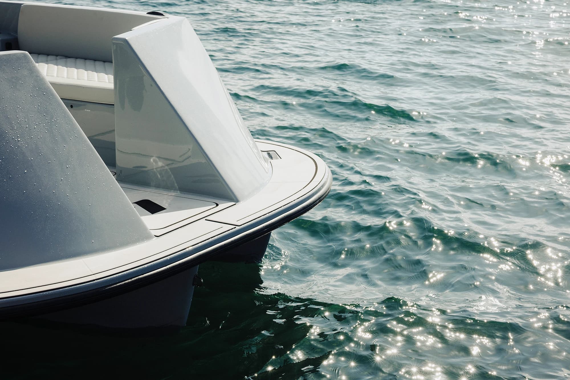Close-up of a sleek off-white electric boat (Halevai model2050) bow and seating area floating on sunlit water.