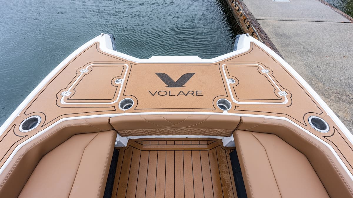 Volare Artemis 23 bow area viewed from above, showing the tan deck, cushioned seating, storage hatches, and dockside water.