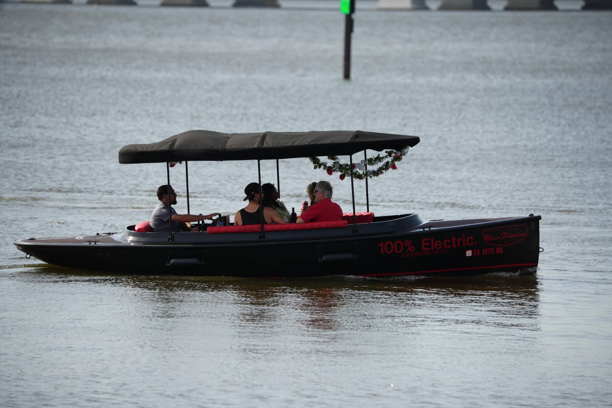 2024 Vision Marine Fantail electric boat carrying passengers on calm water, with canopy and “100% Electric” branding visible on the hull.