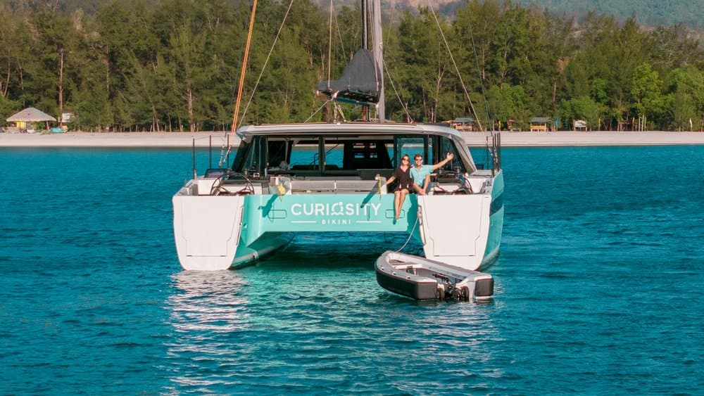 Ocean Cruising Tenders OCT 300 catamaran anchored in turquoise water, with people aboard and a small tender alongside.