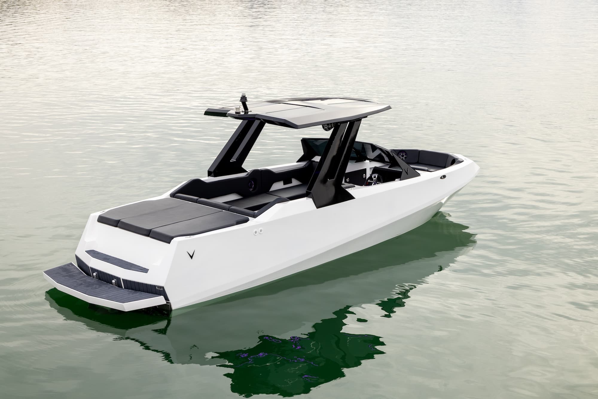 Voltaic AEW24 white electric boat floating on calm water, shown from above with an open cockpit, black T Top, and swim platform.