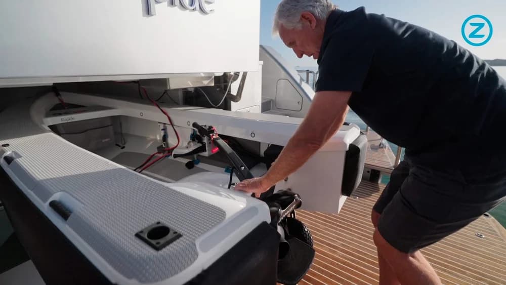 Man securing an Ocean Cruising Tenders OCT 300 on a boat deck, with its electric motor and wiring visible.