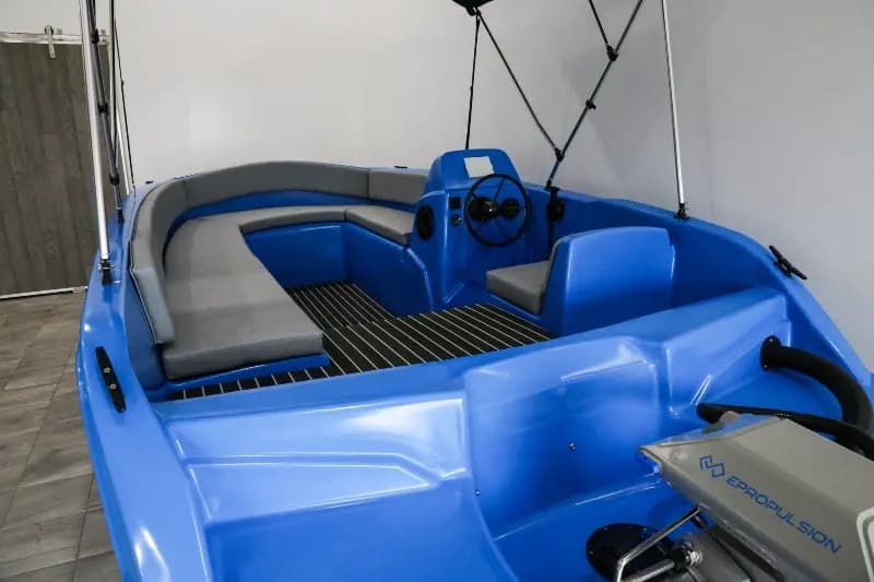 Blue Vision Marine Phantom boat interior with wraparound seating, helm console, and open deck displayed indoors.