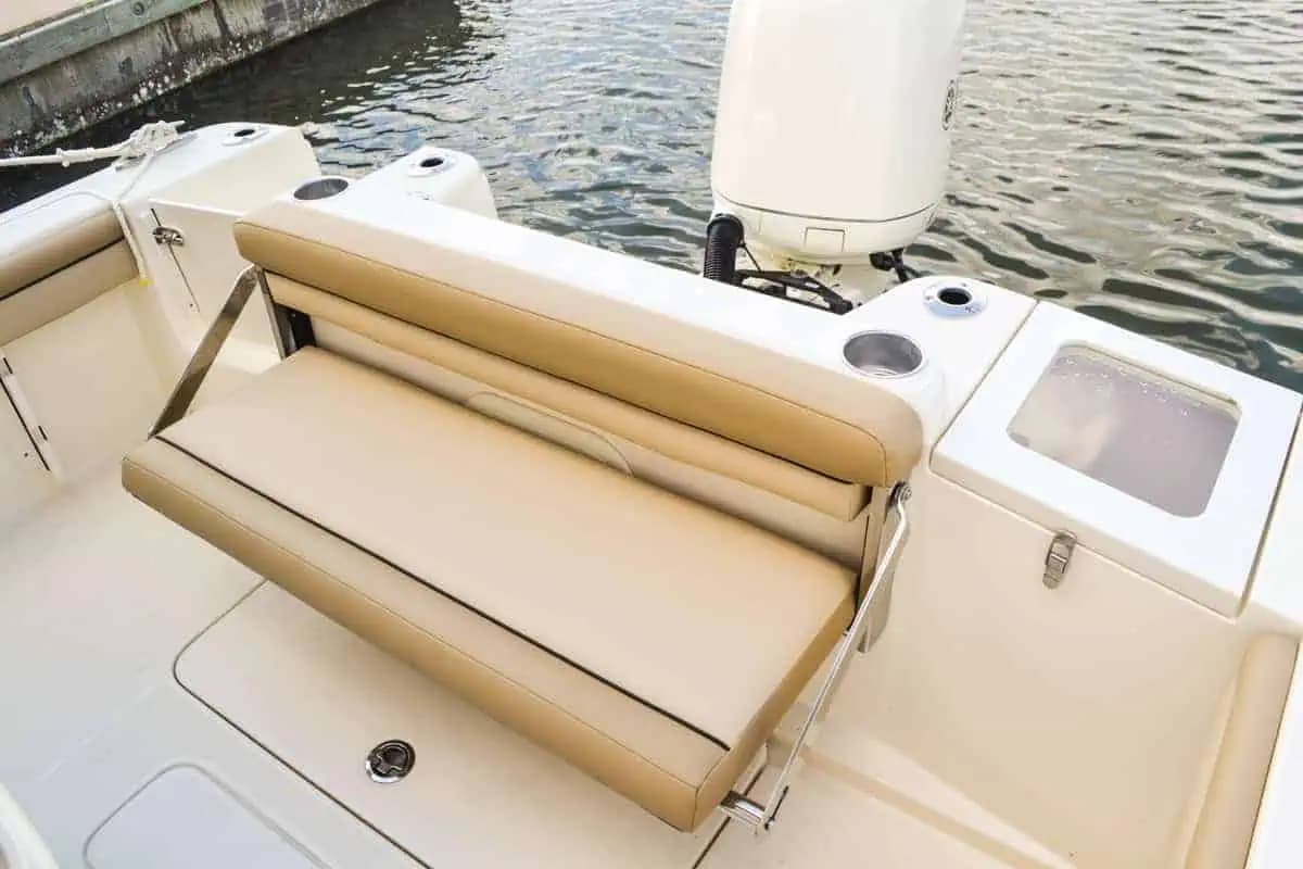 Rear seating area of a Scout 215 XSF, with cushioned bench seating, cup holders, and a stern storage compartment. White Flux outboard motor