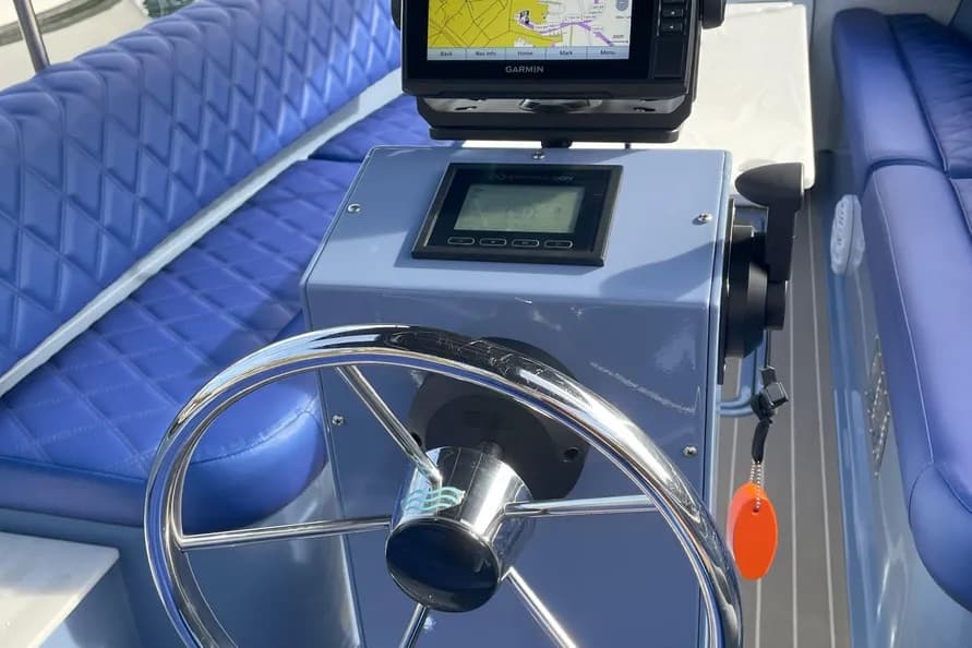 2024 Vision Marina Fantail 217 Boat helm with chrome steering wheel, digital display, Garmin navigation screen, throttle control, and blue quilted seating.