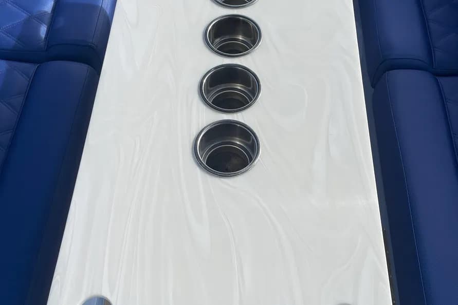 2024 Vision Marine Fantail 217 White center console with four stainless-steel cup holders between dark blue boat seating.