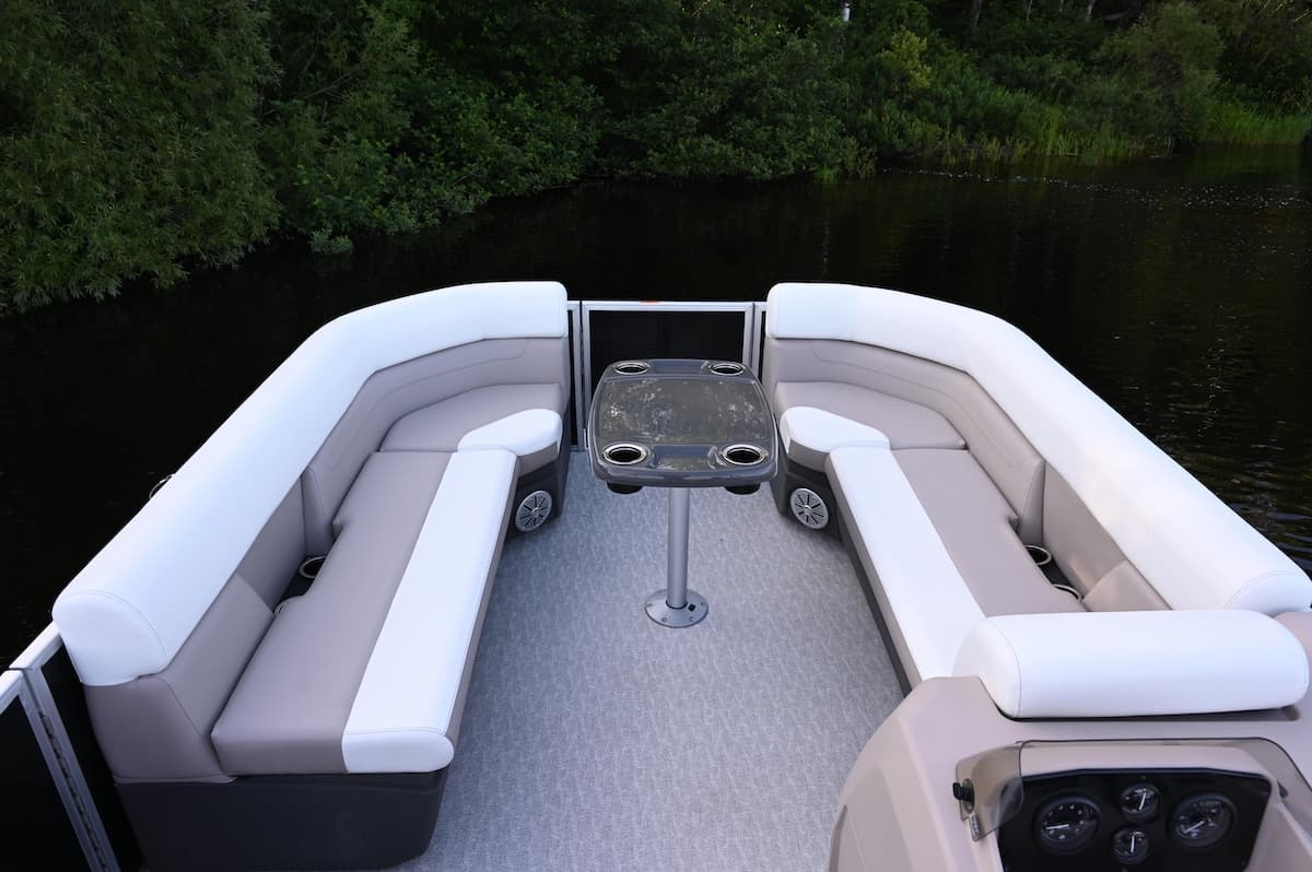 View from the stern into the pontoon boat’s cockpit, showing facing lounge seats, a central table, and helm console (2026 Princecraft Vectra 21 RL).