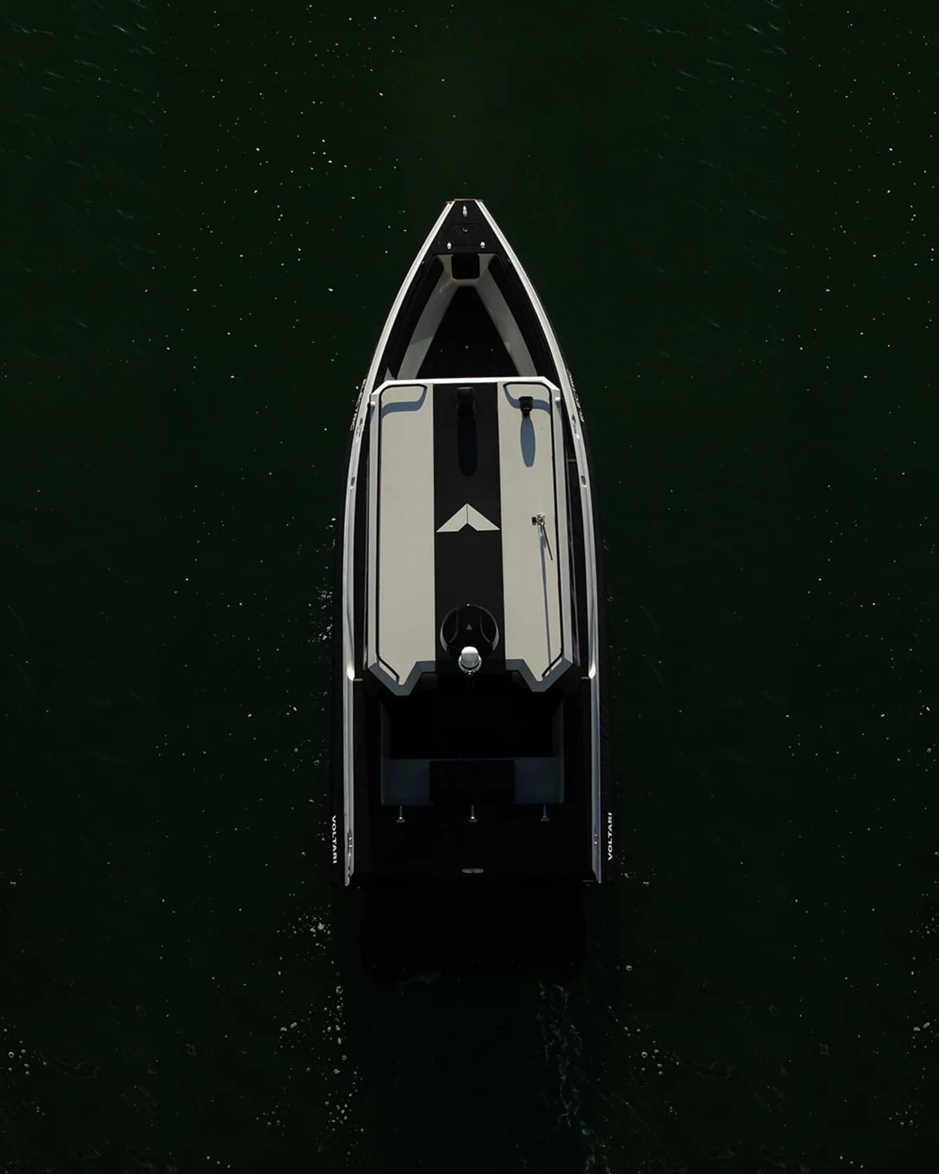 Overhead view of a streamlined boat (2026 Voltari Patrol 26) showing the bow, open cockpit, and rear seating area on dark water.