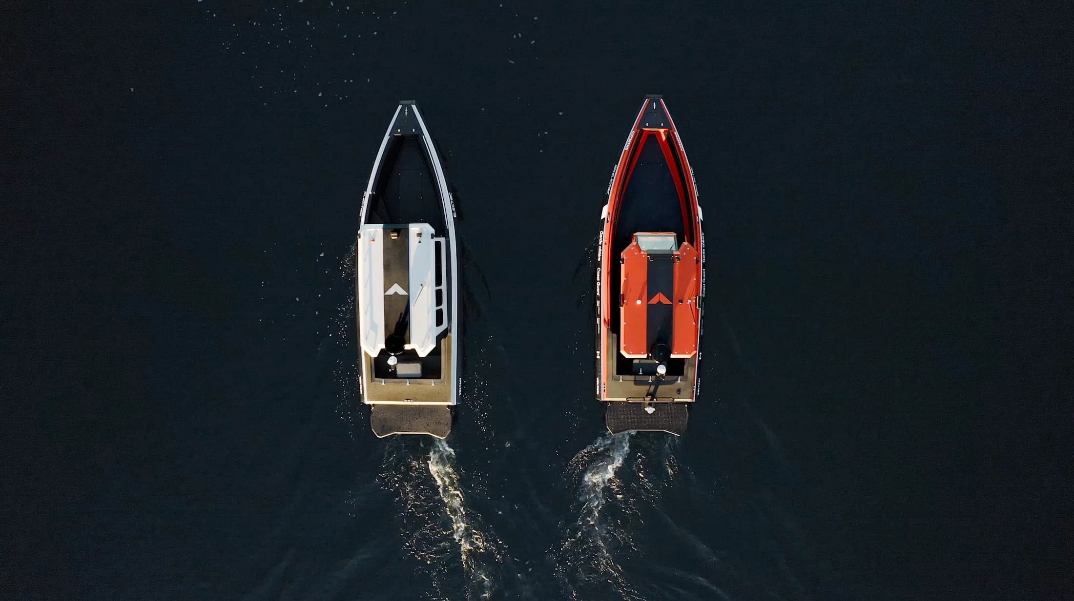 Two sleek patrol boats traveling side by side on dark water, viewed from above, with white and orange interiors and wakes trailing behind (2026 Voltari Patrol 26).