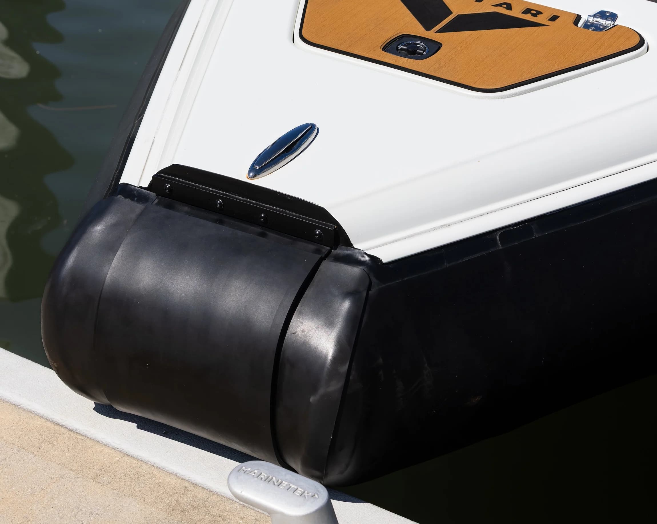 Close-up of the Voltari 260 T/T’s bow, showing a black protective bumper, white deck, and wood-toned forward platform.