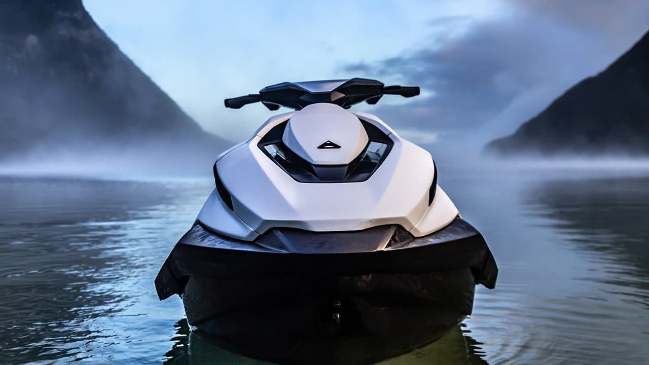 Taiga Orca Performance electric personal watercraft viewed from the front on calm water between misty mountains.