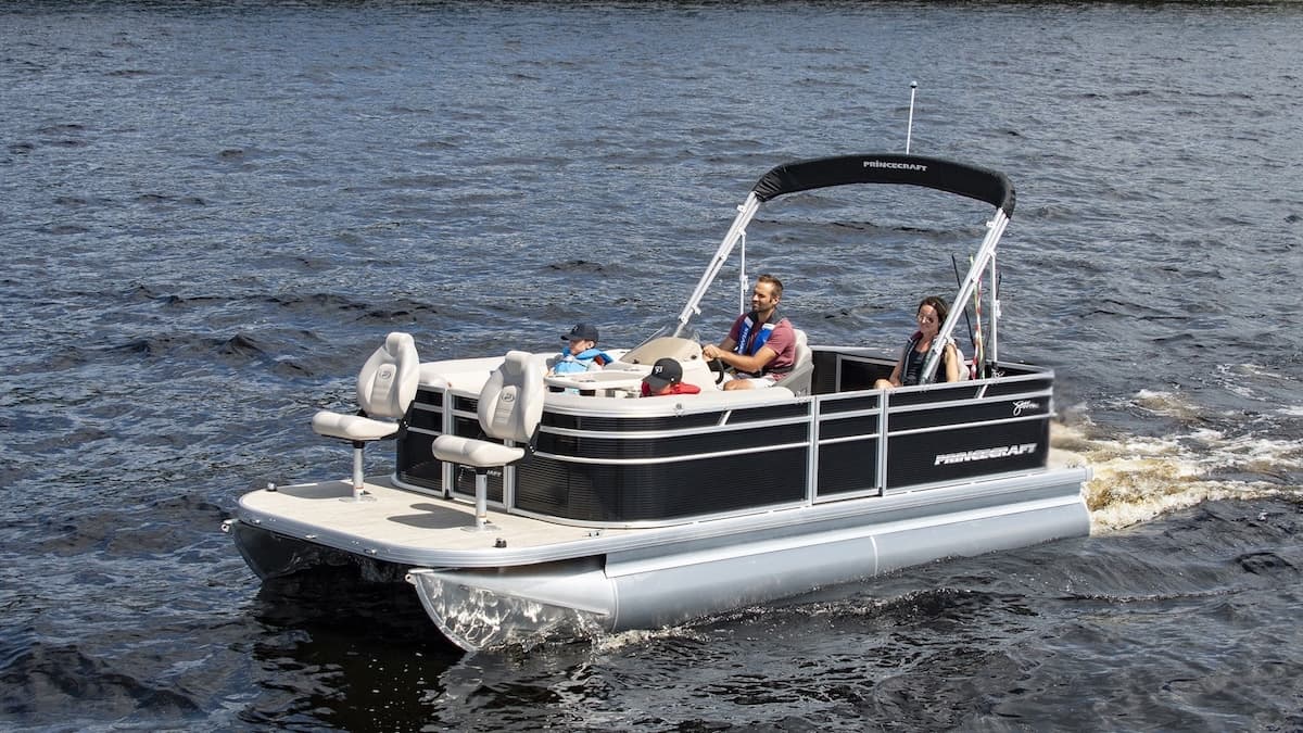 Princecraft Jazz 19 4s pontoon boat underway, viewed from the front-left side, with a black canopy and seated occupants.