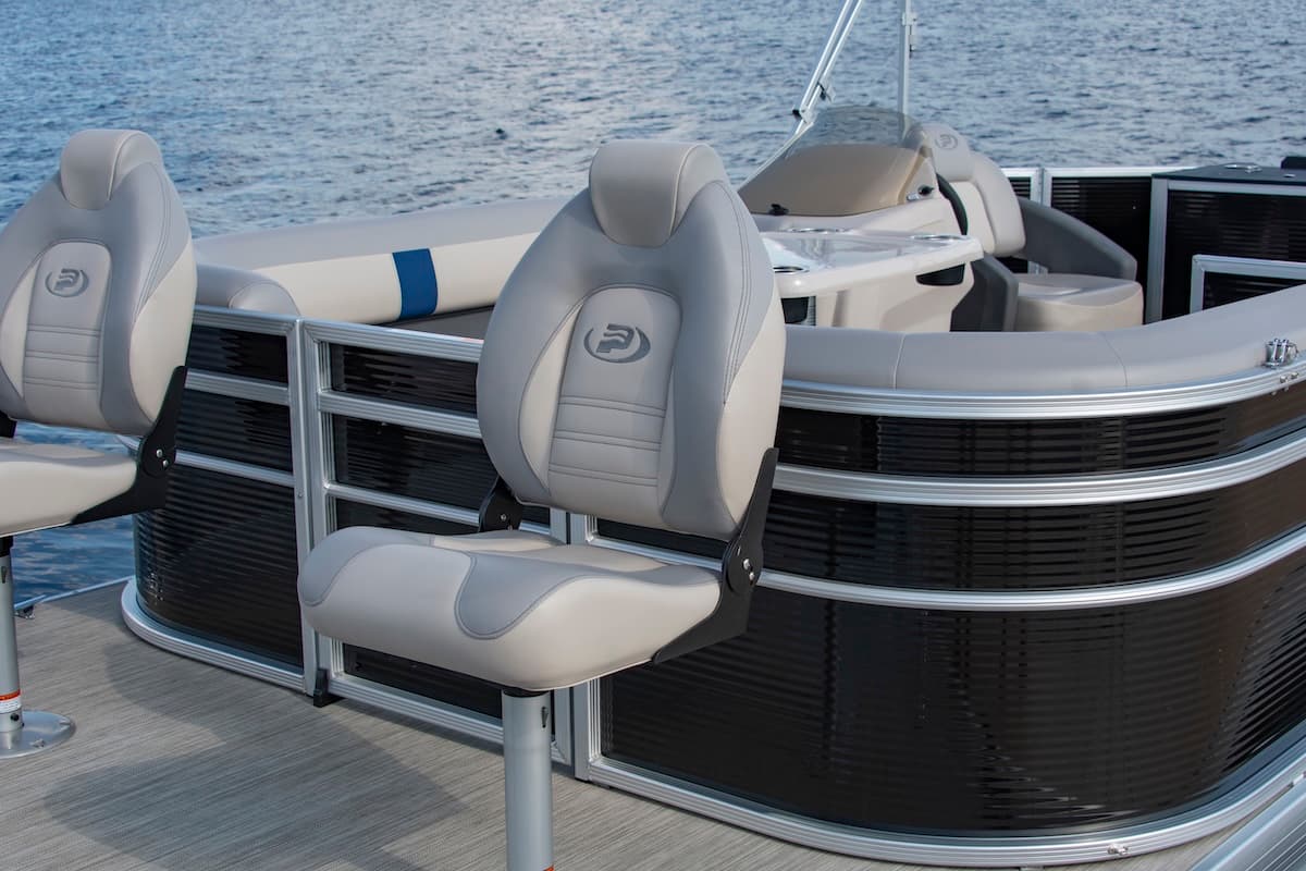 Front seating and console of a Princecraft Jazz 19 4s pontoon boat, viewed from the side with water in the background