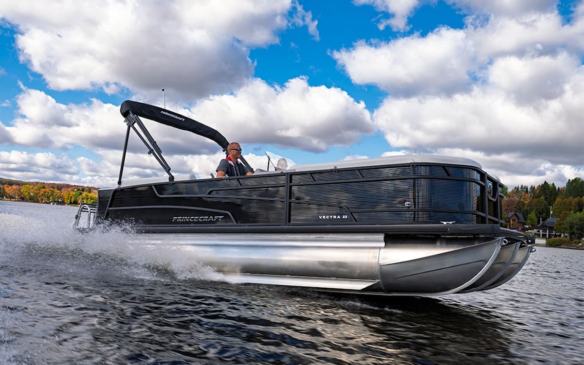 Side view of a Princecraft Vectra 21 RL pontoon boat cruising on a lake, with a raised canopy and wake visible.