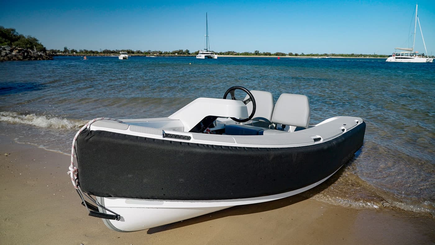 Offshore Cruising Tenders OC330 tender viewed from the port bow, beached at the shoreline with its open cockpit visible