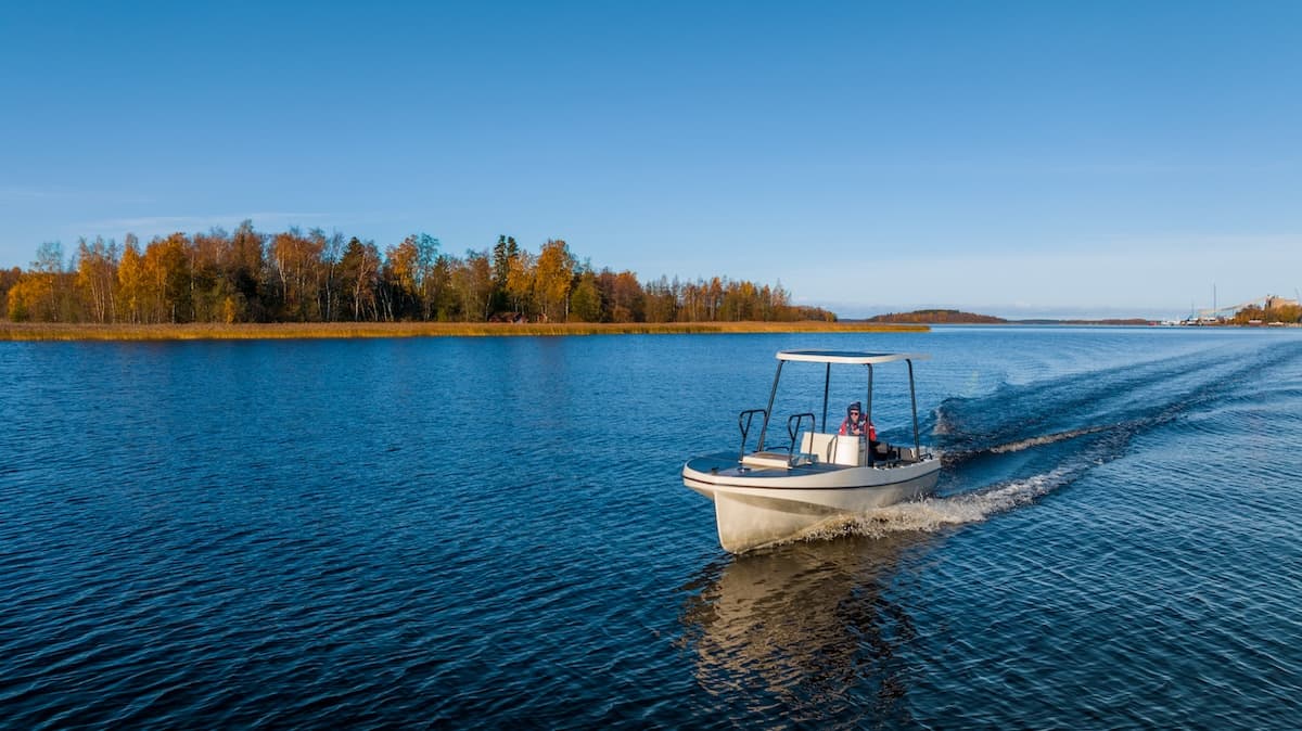 Elvene Amber motorboat cruising across a lake, viewed from behind with autumn shoreline in the background
