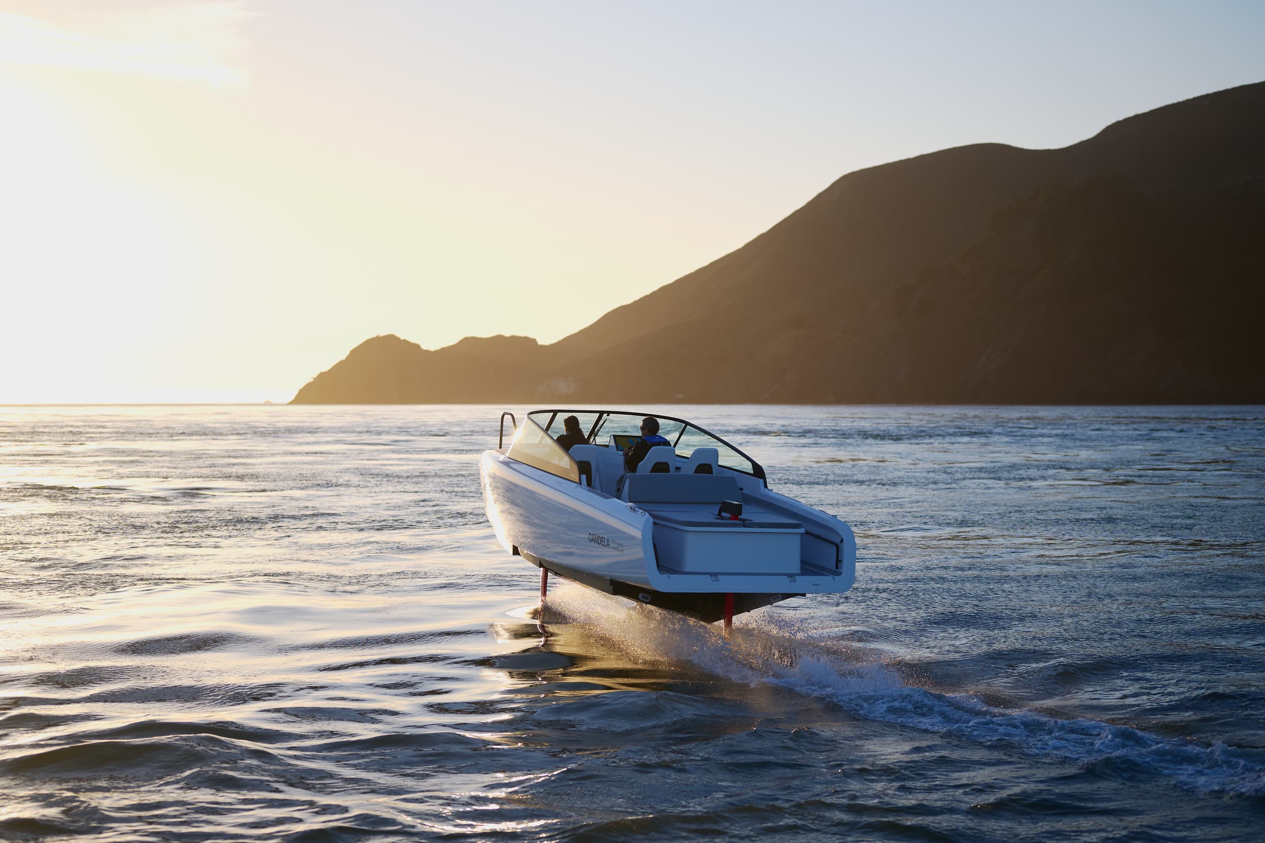 Candela C-8 cruising on open water near a mountainous coastline, viewed from the front-left side.