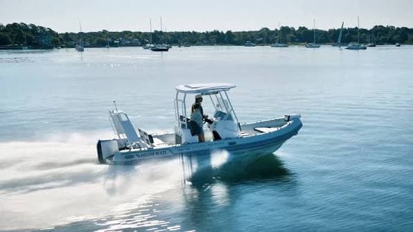 Highfield Sport 660 underway on calm water, viewed from the side, with a person at the helm and a shoreline in the background