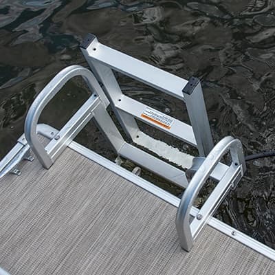 Close view from a pontoon deck (2026 Princecraft Jazz 17) of a mounted aluminum boarding ladder extending into the water.