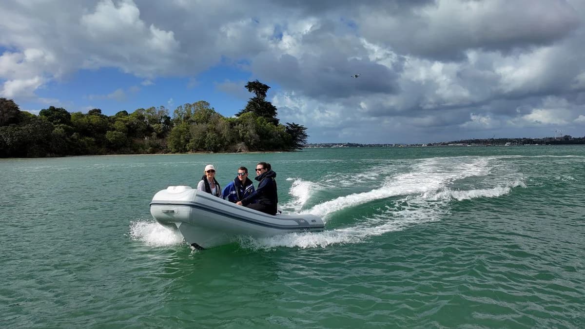 AB T11 underway on open water, viewed from the side with three passengers aboard and a wake trailing behind.