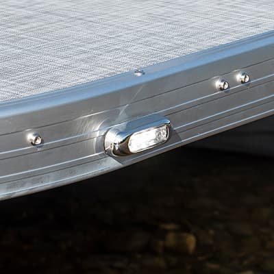 Close-up of a 2026 Princecraft Jazz 19 4s’ aluminum side rail and mounted rectangular light, viewed from the side above the water.
