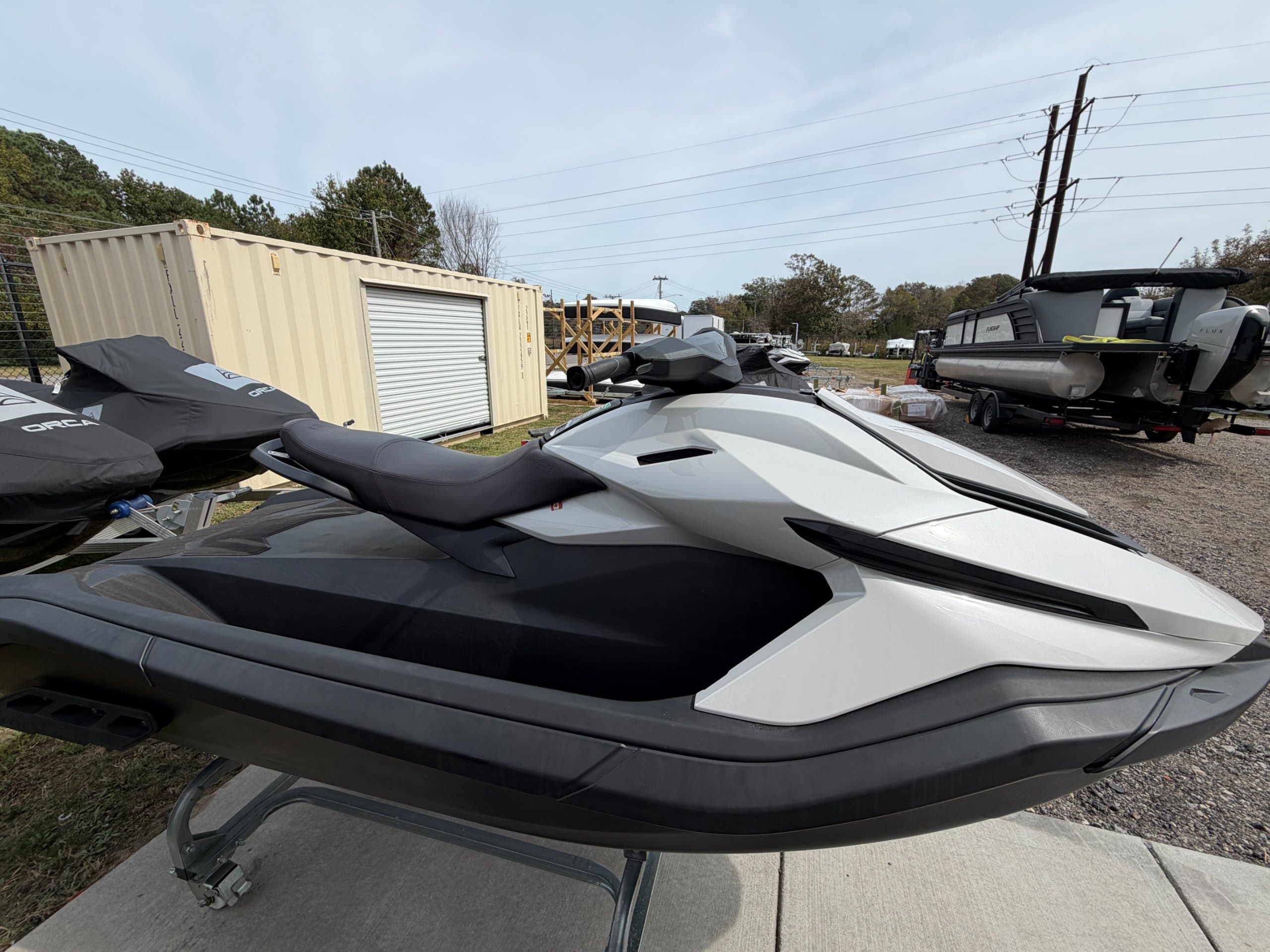 Side view of a white and black personal watercraft on a trailer, with its seat, handlebars, and pointed bow visible.
