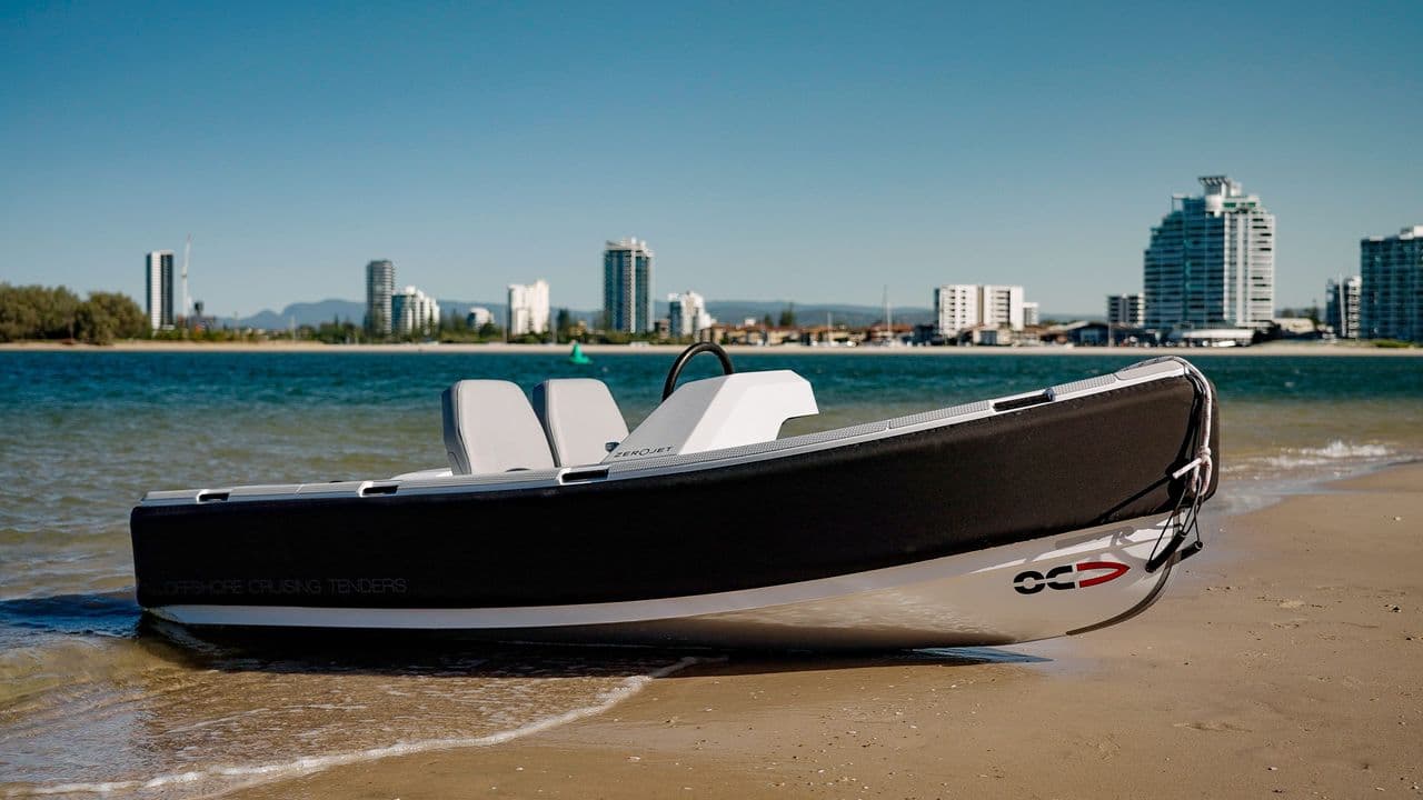 Offshore Cruising Tenders OC330 on a sandy shoreline, viewed from the starboard side with the bow to the right.