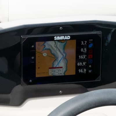 Simrad navigation display with nautical chart and trip data, viewed from the helm behind the steering wheel (2026 Princecraft Vectra 21 RL).