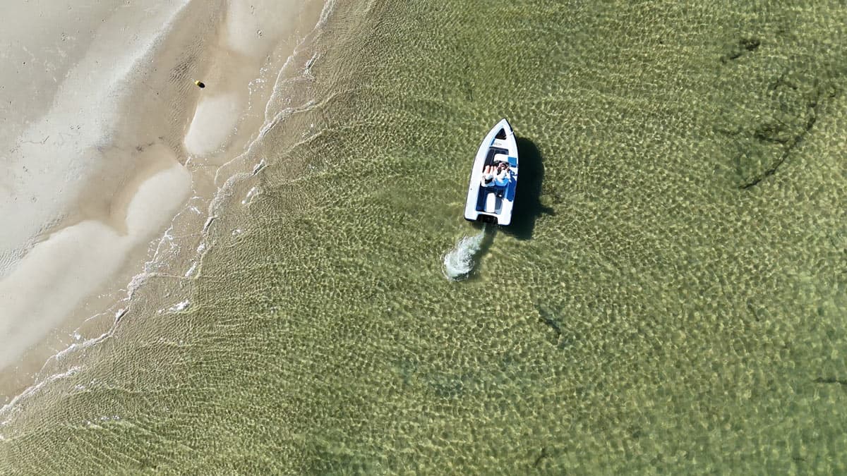 Offshore Cruising Tenders OC330 viewed from above in shallow clear water near a sandy shoreline.