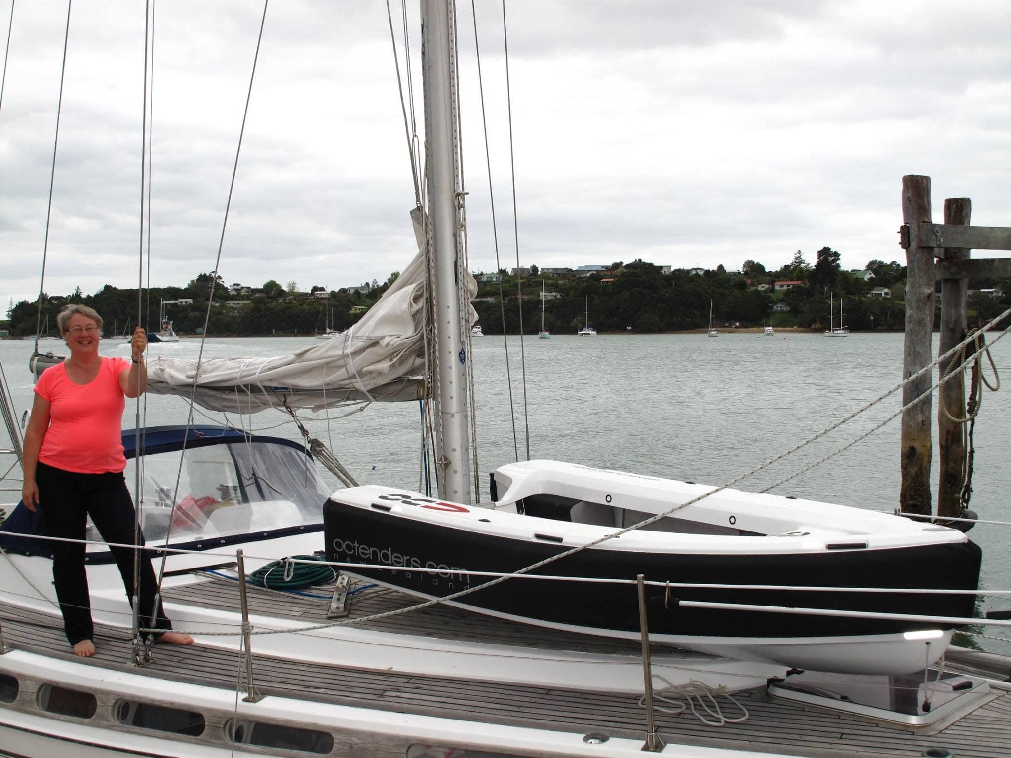 Offshore Cruising Tenders OC330 tender alongside a dock, viewed broadside with a person standing on the adjacent sailboat.