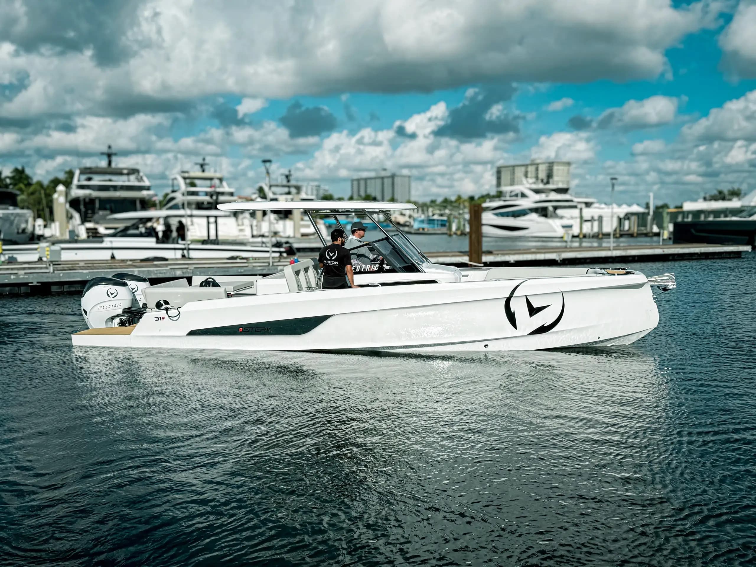 Sterk 31E side view underway on the water, with a person at the helm and marina yachts in the background
