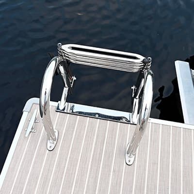 Close-up from above of a stainless-steel boarding ladder mounted on a boat’s (2026 Princecraft Vectra 19 L) swim platform beside dark water
