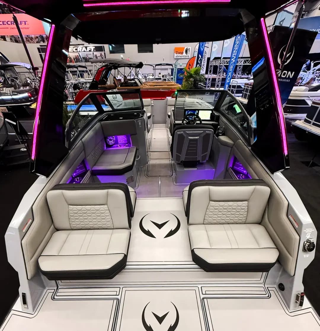 View from the stern into the cockpit of a Vision Marine SPECTR, showing opposing aft seats, helm, and purple accent lighting.