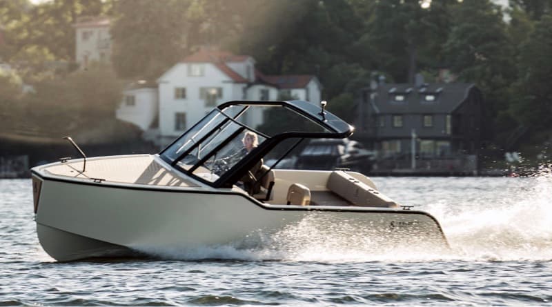 Side view of a X Shore 1 underway, showing the enclosed helm, open bow, and wake on calm water.