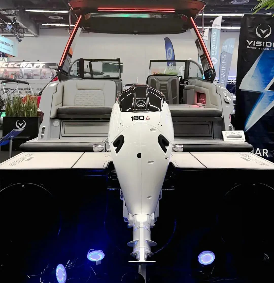 Rear view of a boat (2026 Vision Marine SPECTR) on display, centered on an outboard motor marked “180” between the aft seating and swim platform.