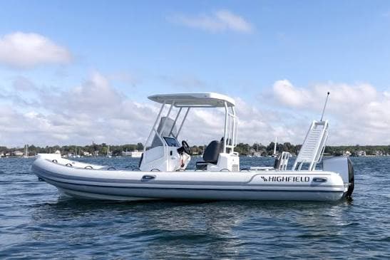 Highfield Sport 660 viewed broadside on the water, showing the full boat with center console, canopy, and stern boarding ladder