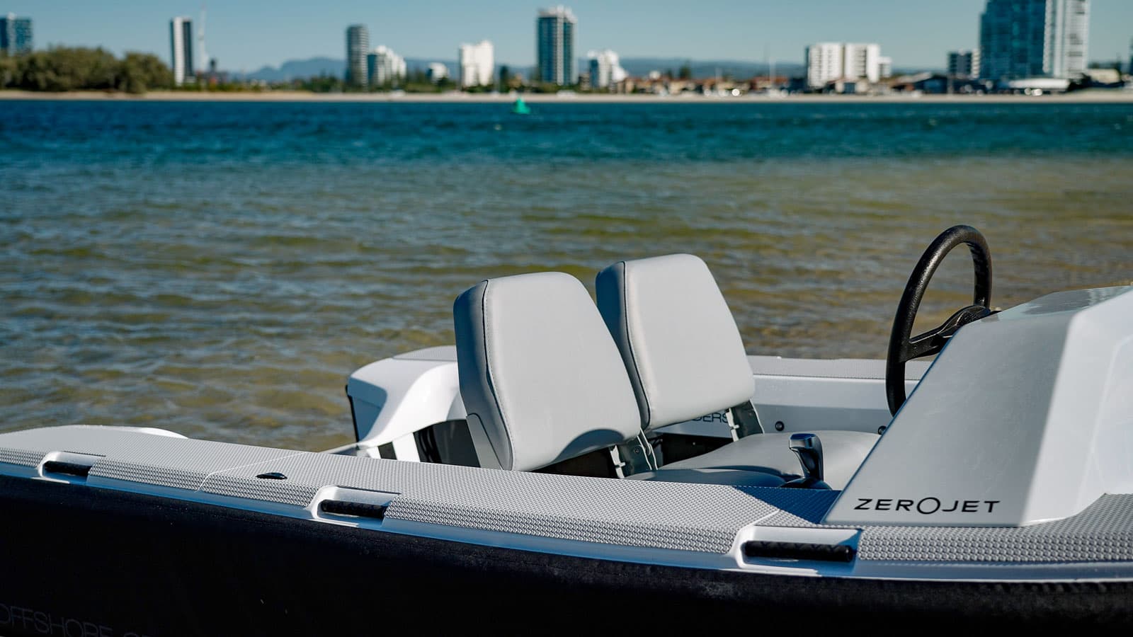 Offshore Cruising Tenders OC330 cockpit and helm viewed from the side, with two seats and waterfront beyond
