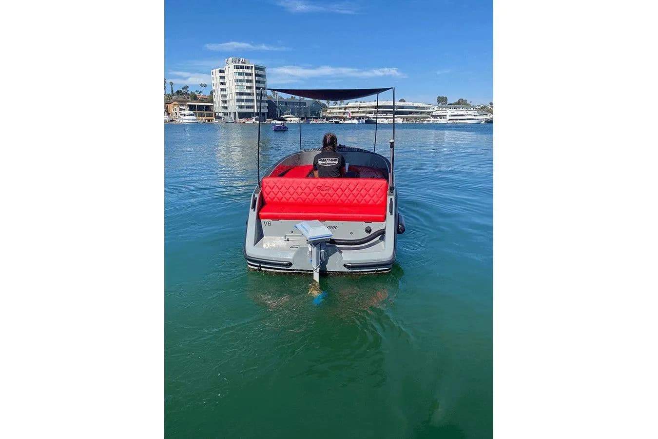 Vision Marine Volt 180 viewed from the stern, showing the red rear seating and boat in the marina.