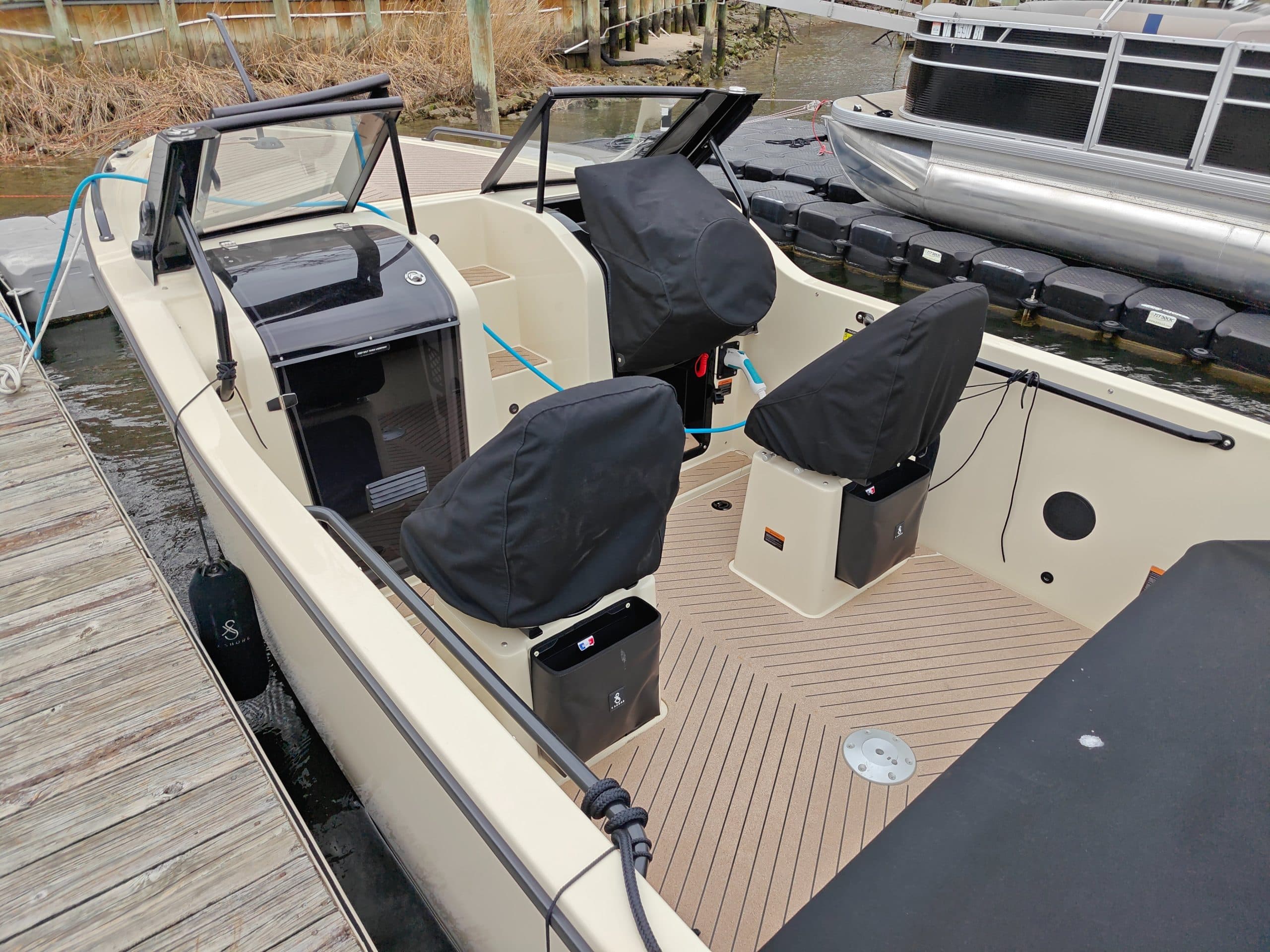 2024 X Shore XShore 1
Open-deck electric boat with covered seats, windshield, steering console, and textured flooring at a marina dock.