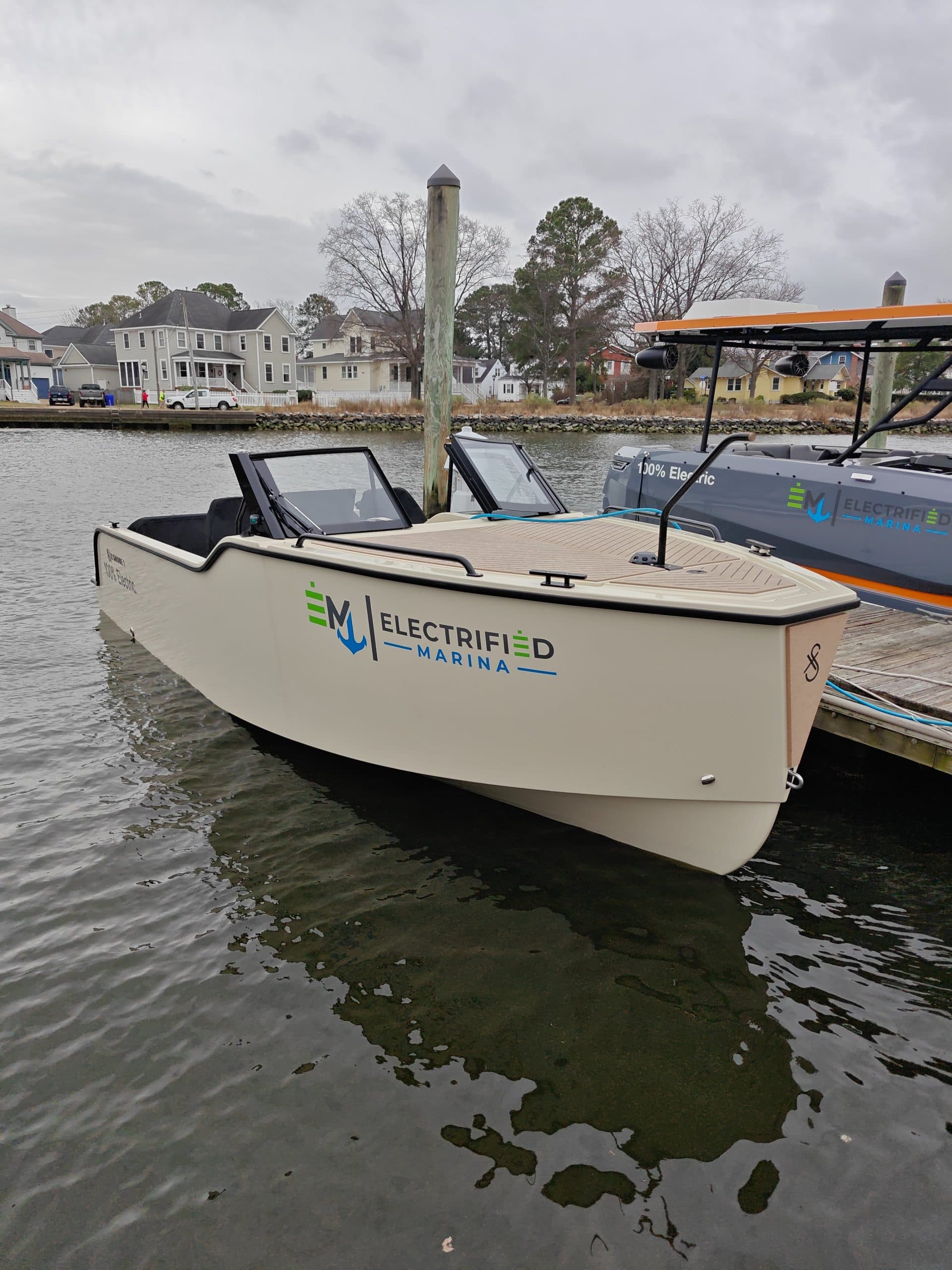 2024 Vision Marine Fantail 217
Electric center-console motorboat docked in calm water, with waterfront homes and a covered boat visible behind it.